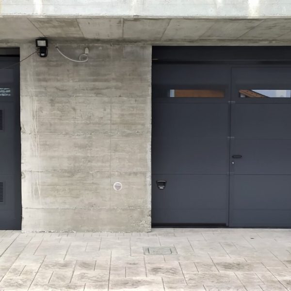 Porta sezionale Modena monodoga liscio colore grigio RAL 7016 con sezione finestrata Adda e porta laterale con griglie di areazione 2021.
