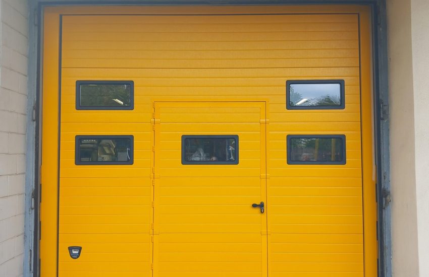 Porta sezionale industriale, con oblò e porta pedonale inserita