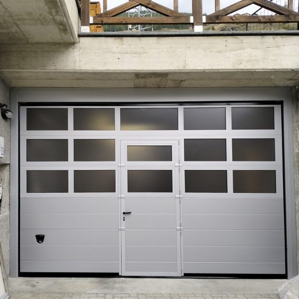 Porta sezionale modello Venezia, RAL 9006, con porta pedonale e sezioni finestrate Adige, motorizzata